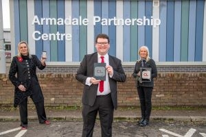 Neighbourhood Manager Anne-Marie Vance, Councillor Andrew McGuire and Customer Service Assistant Rachael Ferguson hold up devices outside Armadale library